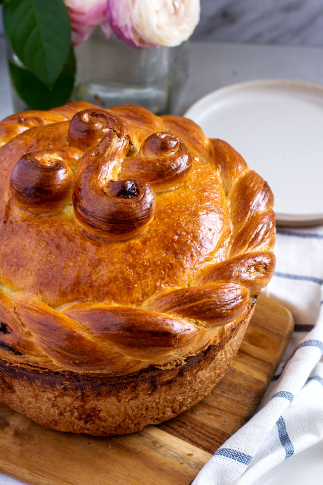 Easter paska with a braided rim and decorative swirls on a wooden board
