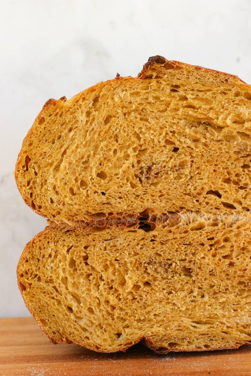 Sourdough pumpkin bread cut in half, with a soft golden crumb