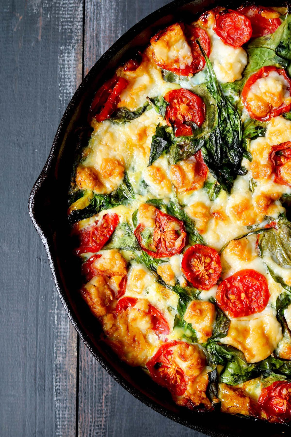 Spinach quiche with golden cherry tomatoes in a cast-iron skillet