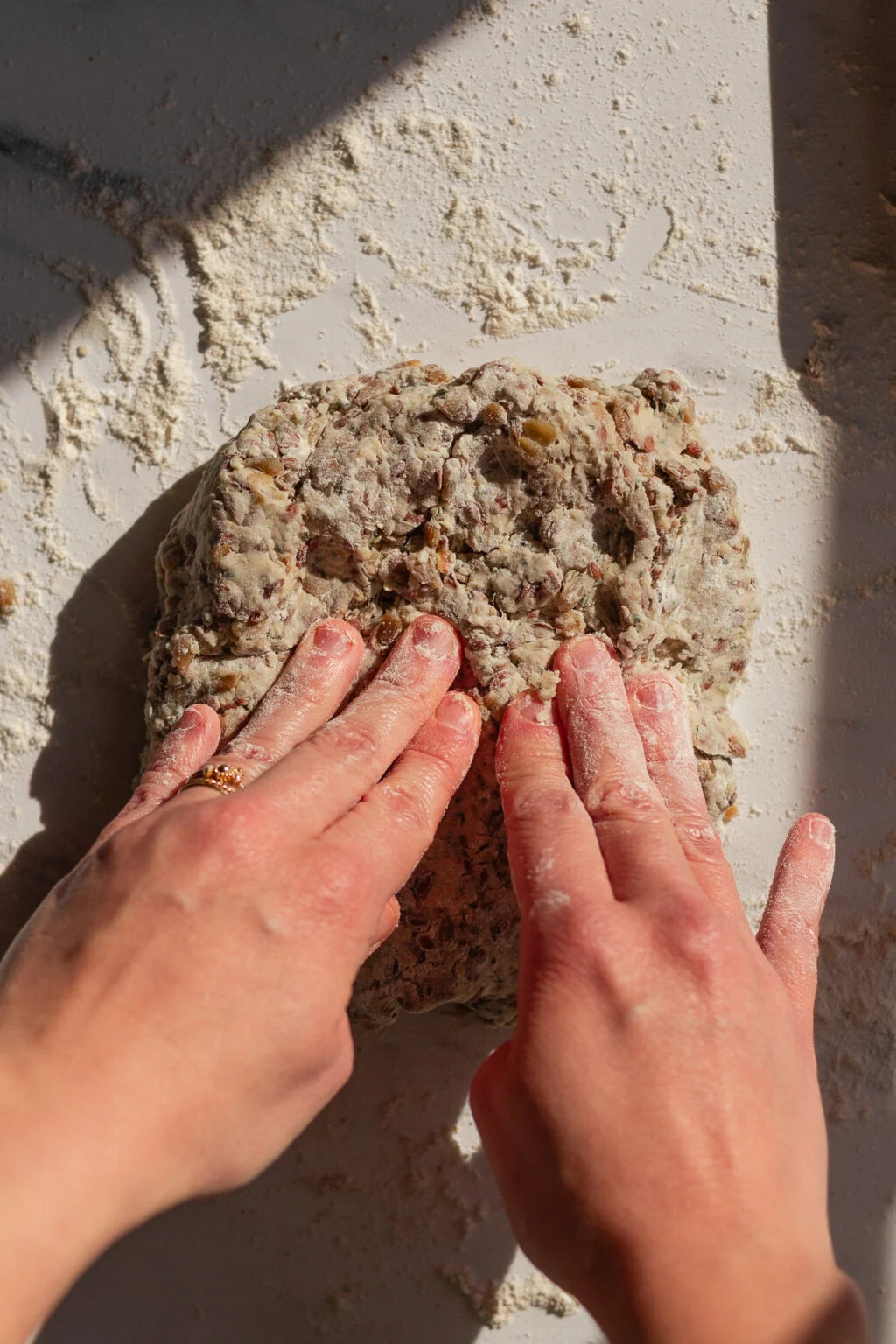 Hands spreading the seed dough on a floured surface