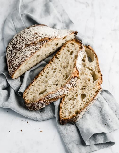 Sliced sourdough loaf on a gray linen cloth
