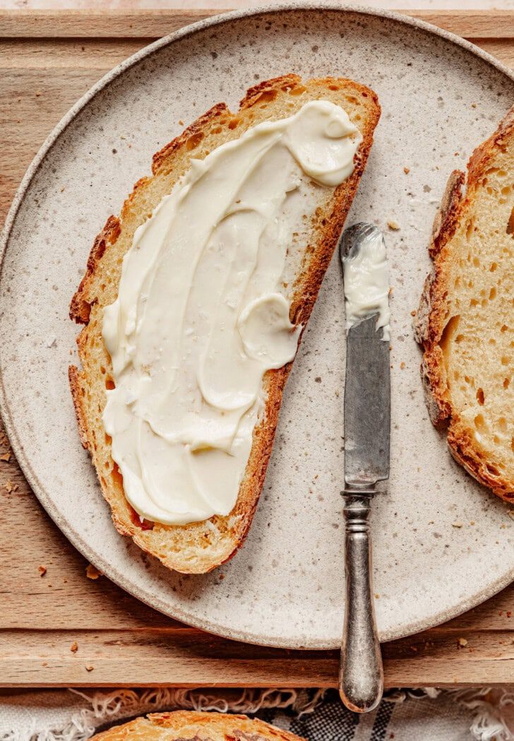 Slice of bread spread with homemade cultured butter next to a knife