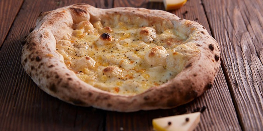 Sourdough cheese pizza with black pepper on a wooden table